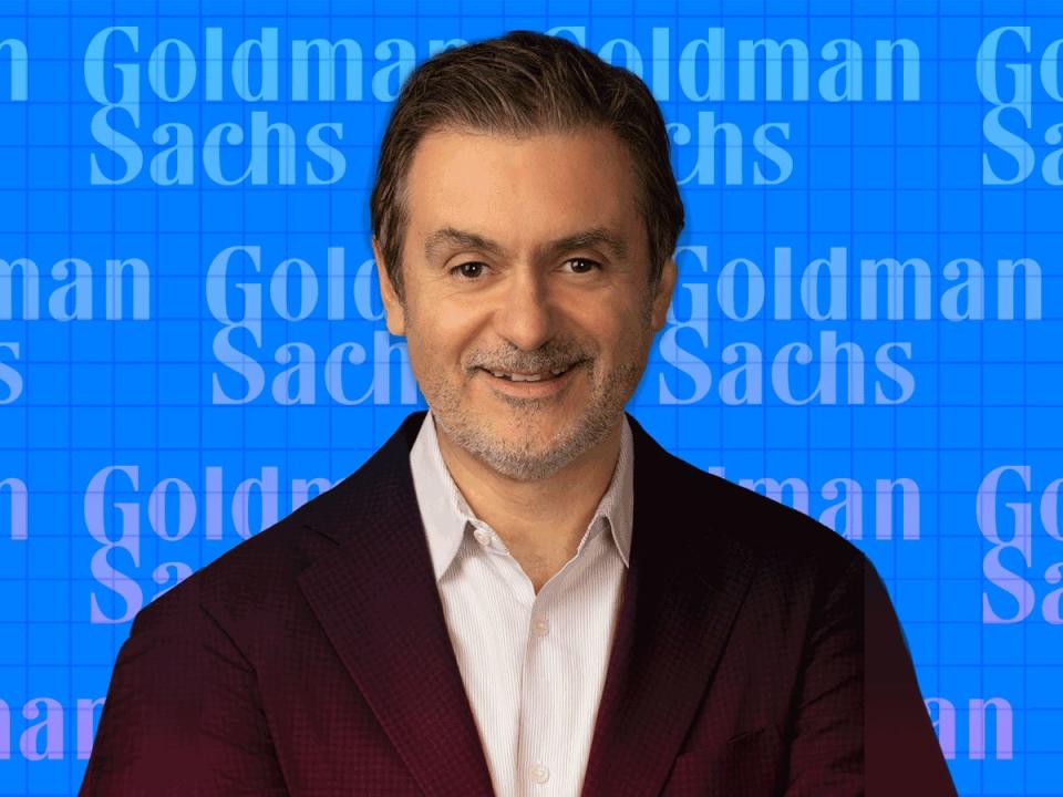 Photo of Marco Argenti over a blue background with several Goldman Sachs logos.