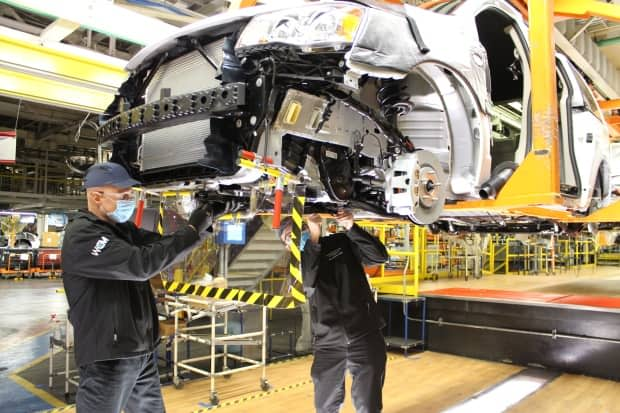 A weld curtain hangs between two operators working on the underbody of a Dodge Grand Caravan at the Windsor Assembly Plant to help maintain social distancing required to slow the spread of coronavirus disease (COVID-19) in Windsor, Ont., on May 8, 2020. (FCA/REUTERS - image credit)