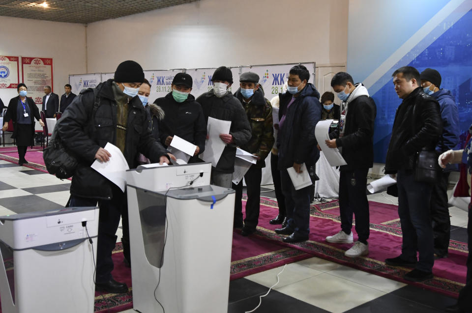 People vote at a polling station during the parliamentary elections in Bishkek, Kyrgyzstan, Sunday, Nov. 28, 2021. Voters in Kyrgyzstan cast ballots in a parliamentary vote Sunday that comes just over a year after a forceful change of government in the ex-Soviet Central Asian nation and is expected to cement the power of President Sadyr Zhaparov. (AP Photo/Vladimir Voronin)