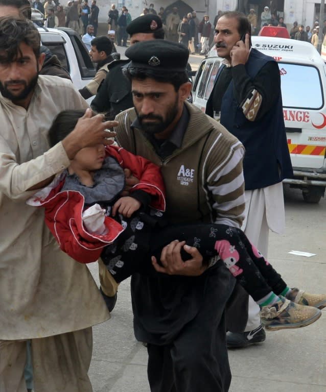 Pakistani men carry an injured student to hospital following a 2014 attack by Taliban gunmen on an army-run school in Peshawar