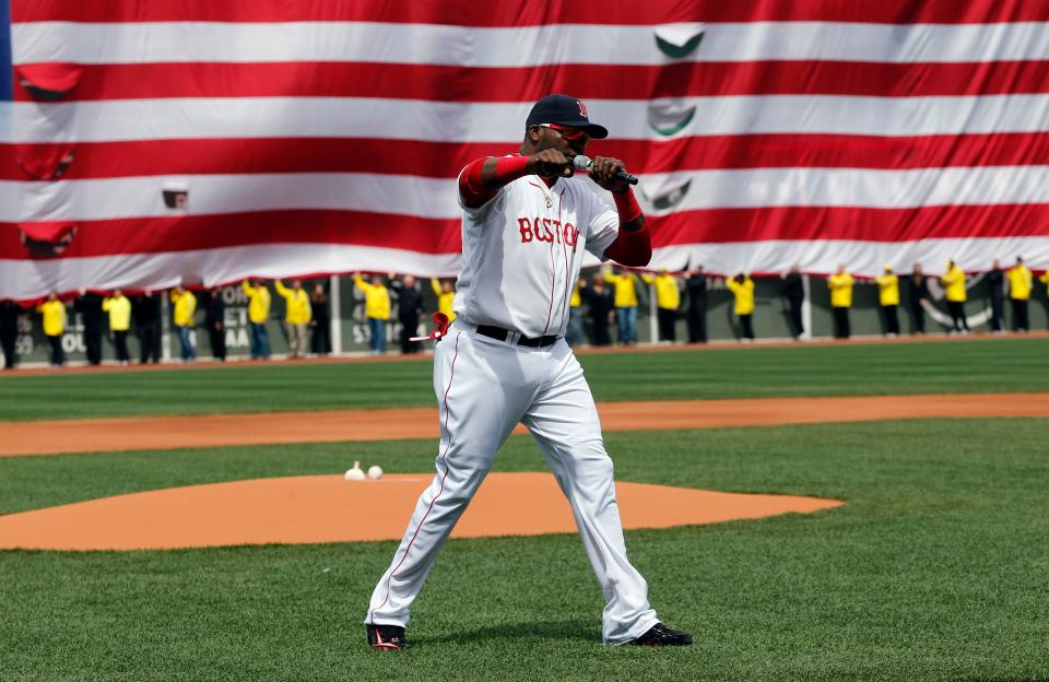 Boston's David Ortiz pumps his fist in front of an American flag and a line of Boston Marathon volunteers, background, after addressing the crowd before the game on April 20, 2013.