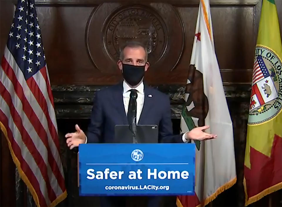 Esta imagen tomada de una transmisión en vivo proporcionada por la oficina del alcalde de Los Ángeles, Eric Garcetti, lo muestra a él con una mascarilla para protegerse del coronavirus, durante su conferencia de prensa diaria, en Los Ángeles, el miércoles 1 de abril de 2020. (Oficina del alcalde Eric Garcetti vía AP)