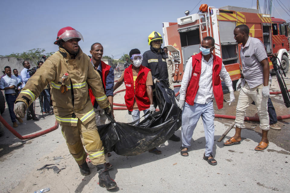 Medical workers carry the body of a civilian who was killed in a suicide car bomb attack that targeted the city's police commissioner in Mogadishu, Somalia Saturday, July 10, 2021. At least nine people are dead and others wounded after the large explosion, a health official at the Medina hospital said, noting that the toll reflected only the dead and wounded brought there. (AP Photo/Farah Abdi Warsameh)