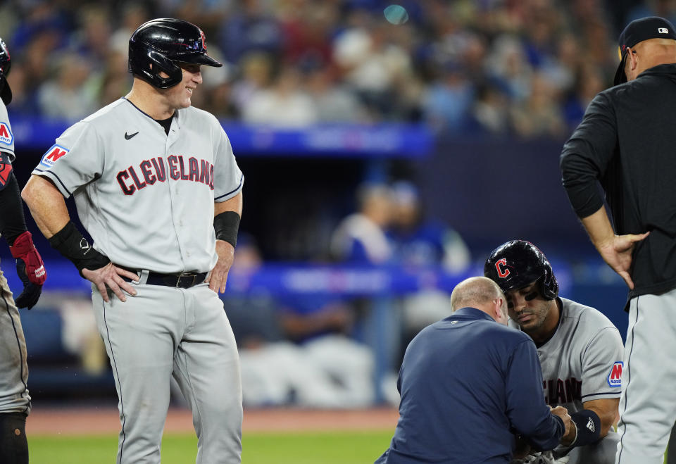 A trainer works on Cleveland Guardians' Ramon Laureano, second right, after he was hit by a pitch against the Toronto Blue Jays as teammate Kole Calhoun, left, looks on during the sixth inning of a baseball game in Toronto on Saturday, Aug. 26, 2023. (Frank Gunn/The Canadian Press via AP)