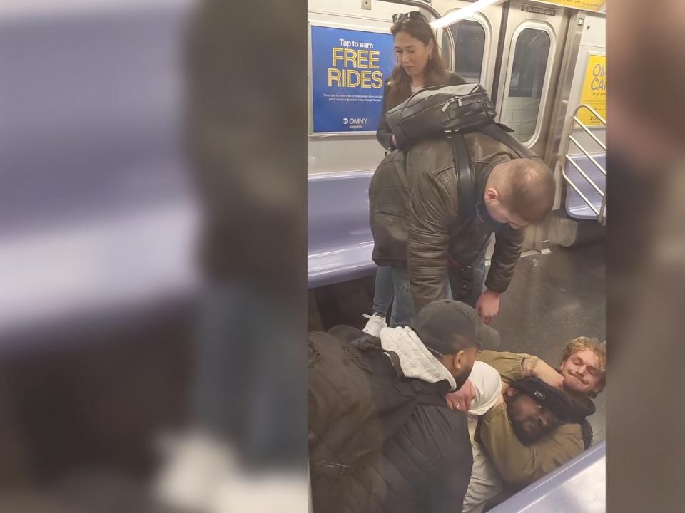 Three men, including Daniel Penny on the right, restrain Jordan Neely on the floor of a subway train in this still image from a video.