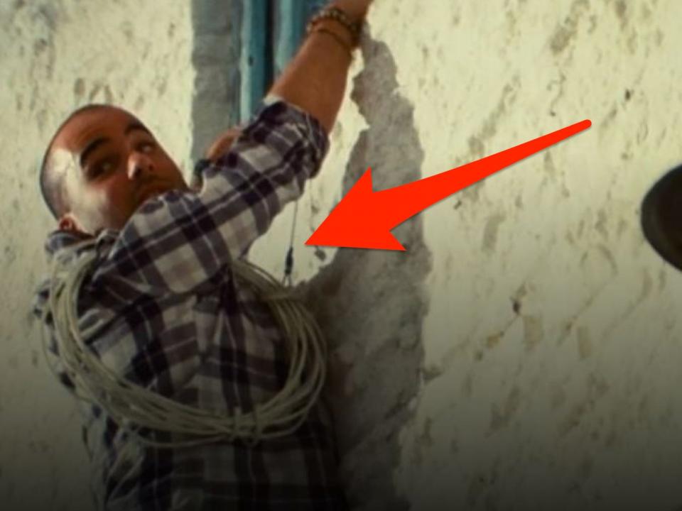 red arrow pointing at a safety wire hold up an ensemble member in a scene in mamma mia