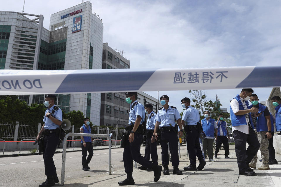 Police officers stand guard outside Apple Daily headquarters as Hong Kong media tycoon Jimmy Lai, who founded local newspaper Apple Daily, is arrested by police officers at his home in Hong Kong, Monday, Aug. 10, 2020. Hong Kong police arrested Lai and raided the publisher's headquarters Monday in the highest-profile use yet of the new national security law Beijing imposed on the city after protests last year. (AP Photo/Vincent Yu)