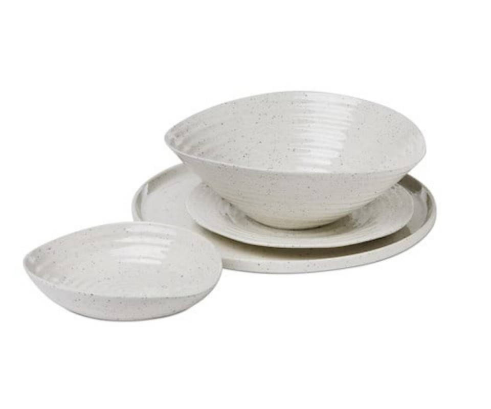 A white bowl sits on the left next to a larger white serving bowl sitting on two plates behind a white background.