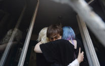 Activist Malgorzata Szutowicz, center, known as Margot, is hugged before being arrested in Warsaw, Poland, on Friday Aug. 7, 2020. LGBT rights activists scuffled with police Friday in Warsaw after turning out on the streets to protest the arrest of an an activist. According to Polish media reports, the activist was placed under two-months arrest Friday for protest actions against anti-homosexual attitudes. After the person was arrested in central Warsaw, protesters surrounded the police car and one person climbed on top of it. (AP Photo/Czarek Sokolowski)