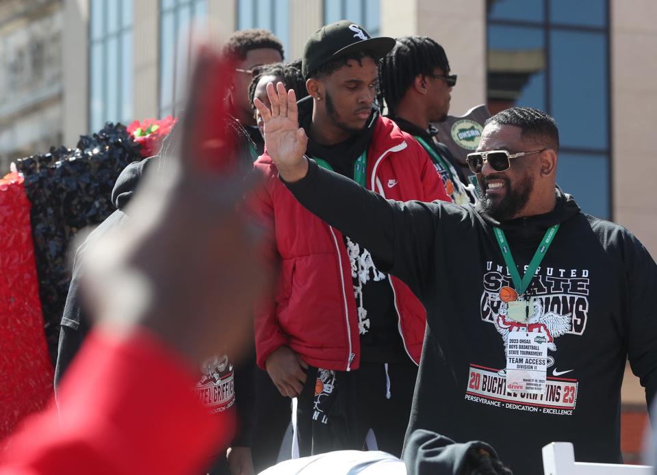 Buchtel coach Rayshon Dent waves to the crowd as he and his players ride in the Akron Parade of Champions on Main Street to celebrate state basketball champions Buchtel and Archbishop Hoban high schools in Akron on March 26.