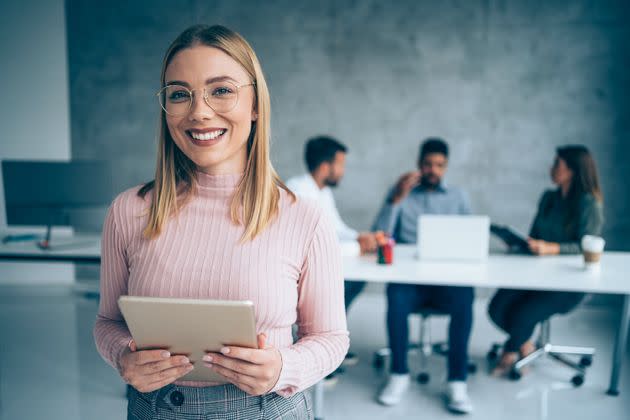 Shot of a beautiful smiling businesswoman standing in front of her team and holding digital tablet. Portrait of successful businesswoman standing with her colleagues working in background. Multi-ethnic group of creative people on a business meeting in board room. (Photo: VioletaStoimenova via Getty Images)