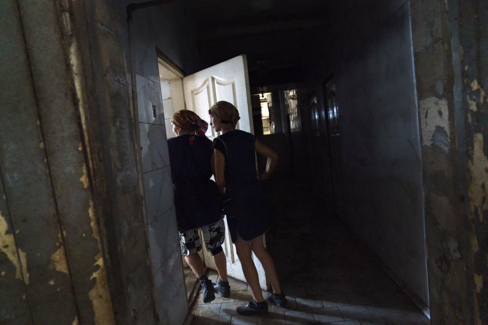 Halyna Borysenko, right, and Nataliia Onatska walk into the pumping room to prepare cows for milking at the KramAgroSvit dairy farm in Dmytrivka, Donetsk region, eastern Ukraine, Wednesday, Aug. 10, 2022. The farm is producing only two tons of milk per day now, compared to 11 tons before the war, and it's slaughtered and sold all of the pigs and rabbits that it once raised. (AP Photo/David Goldman)