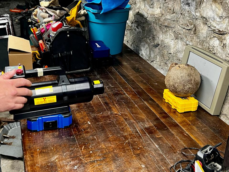 A bomb squad member uses a portable X-ray machine on a cannonball found underground at the John Bliss House in Newport.