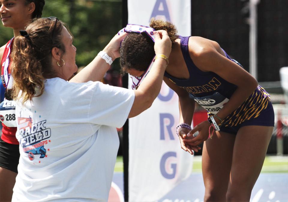 Hickman's Athena Peterson accepts a third-place medal after the  Class 5 jong jump event during the second day of the MSHSAA state track and field championship meet on May 27, 2023, in Jefferson City, Mo.