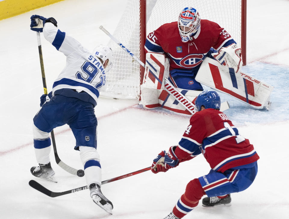 Tampa Bay Lightning's Steven Stamkos (91) takes a shot on Montreal Canadiens goaltender Sam Montembeault (35) as Canadiens' Nick Suzuki (14) skates in during the second period of an NHL hockey game, Tuesday, Nov. 7, 2023 in Montreal. (Christinne Muschi/The Canadian Press)