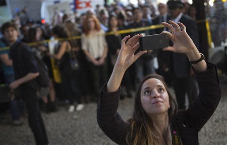 A woman takes a photo of a new installation by British graffiti artist Banksy in New York October 18, 2013. REUTERS/Carlo Allegri