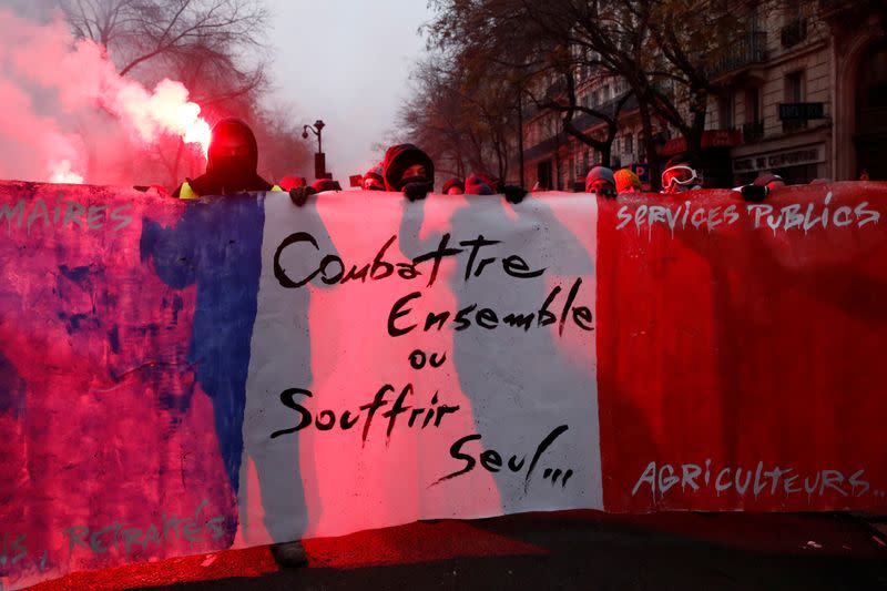 Manifestantes sostienen una pancarta durante una manifestación contra los planes de reforma de pensiones del gobierno francés en París. El eslogan dice "Luchad juntos o sufrid solos".