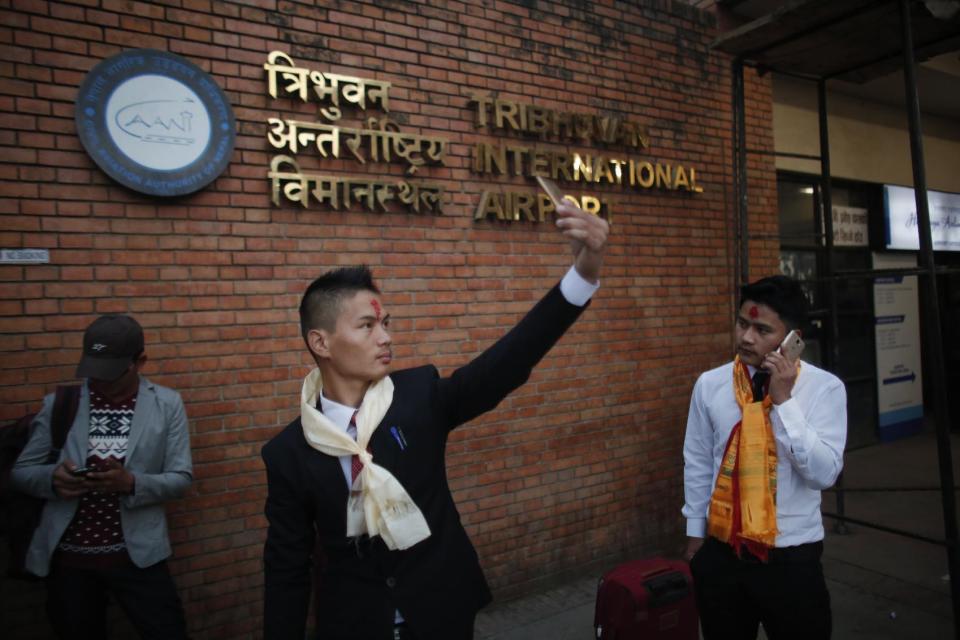 In this photo taken on Monday, Nov. 28, 2016, a Nepali Prem Bahadur Ale Magar, 23, takes a selfie while he waits for his flight to Malaysia, where he will work in a warehouse as a cleaner, at Tribhuwan International airport in Kathmandu, Nepal. The number of Nepali workers going abroad has more than doubled since the country began promoting foreign labor in recent years: from about 220,000 in 2008 to about 500,000 in 2015. The unskilled workers fill a host of global demands: building highways, stadiums and houses in Gulf states and guarding shopping malls, sewing sweatshirts and assembling televisions in Malaysia. (AP Photo/Niranjan Shrestha)