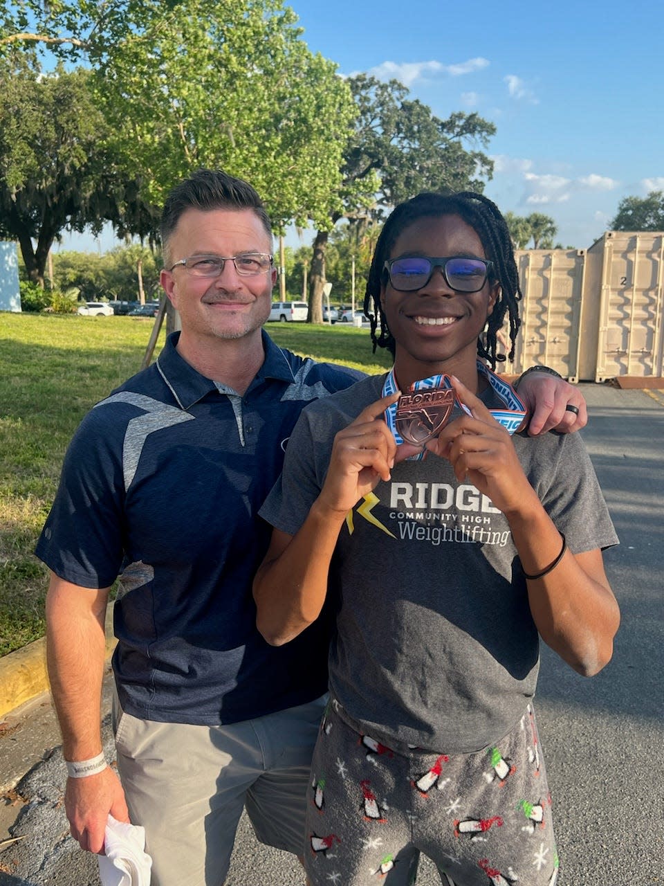 Standing here are Ridge head weightlifting coach Earl Sly, left, and weightlifter A-Jay Saint Louis. Saint Louis took third in the boys state weightlifting championships Friday at the RP Funding Center.