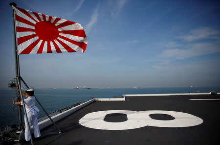 A sailor raises the Japanese naval ensign on the deck of Japanese helicopter carrier Kaga before its departure for naval drills in the Indian Ocean, Indonesia September 22, 2018. Picture taken on September 22, 2018. REUTERS/Kim Kyung-Hoon