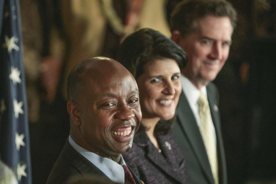 FILE - Rep. Tim Scott smiles as he listens to Sen. Lindsey Graham, R-S.C., after being officially introduced by South Carolina Gov. Nikki Haley, center, to fill the vacant U.S. Senate seat vacated by departing Sen. Jim DeMint, far right. (Tim Dominick/The State via AP, File)