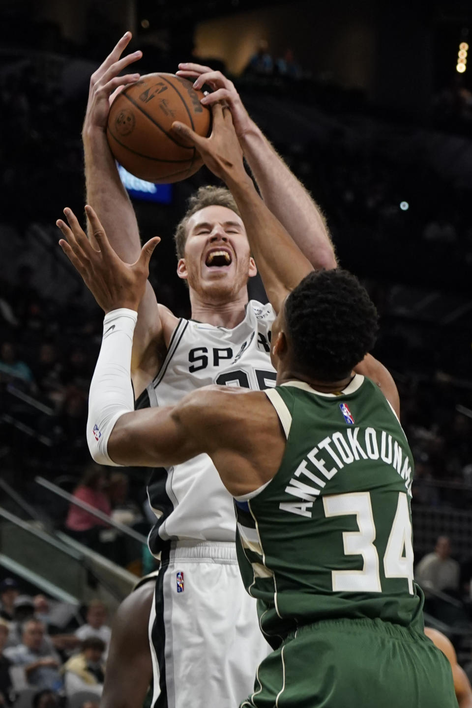 San Antonio Spurs' Jakob Poeltl (25) tries to shoot over Milwaukee Bucks' Giannis Antetokounmpo (34) during the first half of an NBA basketball in San Antonio, Texas, Saturday, Oct. 23, 2021. (AP Photo/Chuck Burton)