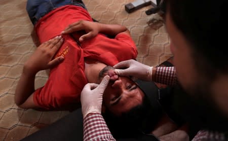 Displaced Syrian refugee boy attends a session at a physiotherapy clinic inside a large tent in the border village of Shamarin