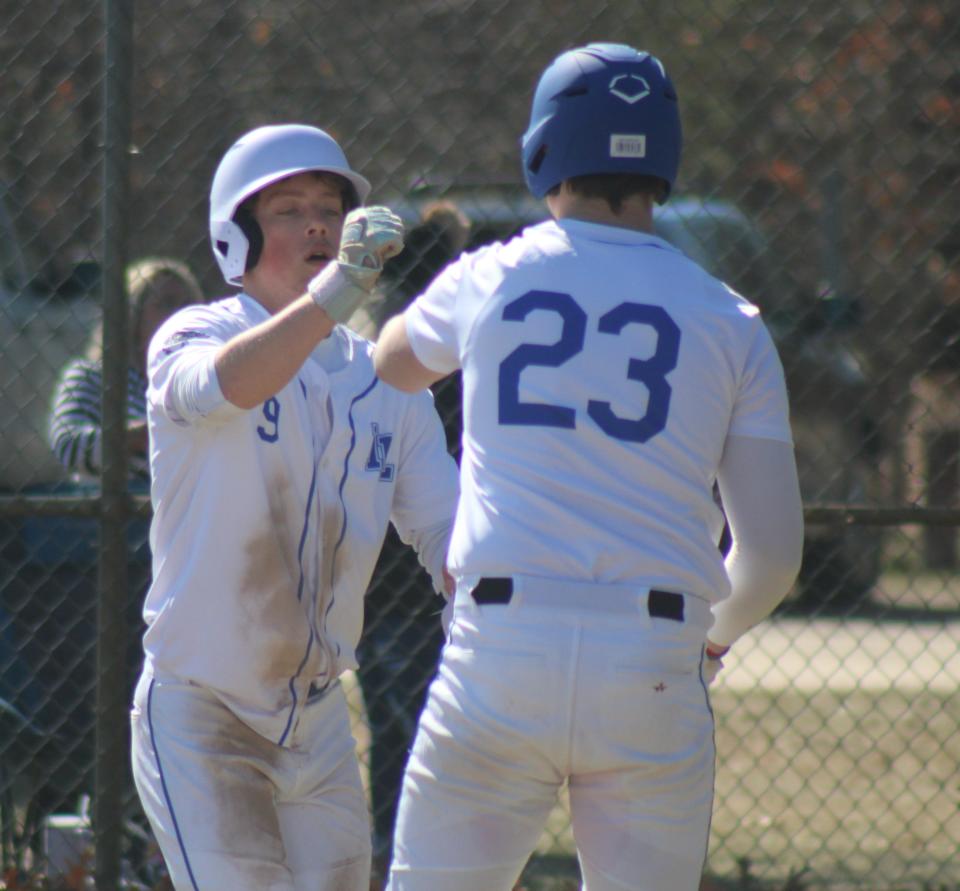 Inland Lakes seniors Connor Wallace (left) and Jake Willey (23) celebrate a run scored during game one of Tuesday's home baseball doubleheader against Onaway at Cooperation Park.