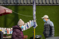 People wearing face masks to protect against the spread of the coronavirus walk past a newsstand in Beijing, Wednesday, Jan. 20, 2021. China is now dealing with coronavirus outbreaks across its frigid northeast, prompting additional lockdowns and travel bans. (AP Photo/Mark Schiefelbein)