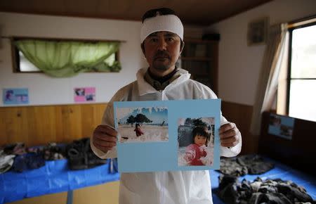 Norio Kimura, 49, who lost his father, wife and daughter in the March 11, 2011 tsunami, poses with portraits of his daughter Yuna as he organizes his family's personal belongings, washed by the tsunami, at a temple near his home land inside the exclusion zone in Okuma town, near Tokyo Electric Power Co's (TEPCO) tsunami-crippled Fukushima Daiichi nuclear power plant February 23, 2015. REUTERS/Toru Hanai/Files
