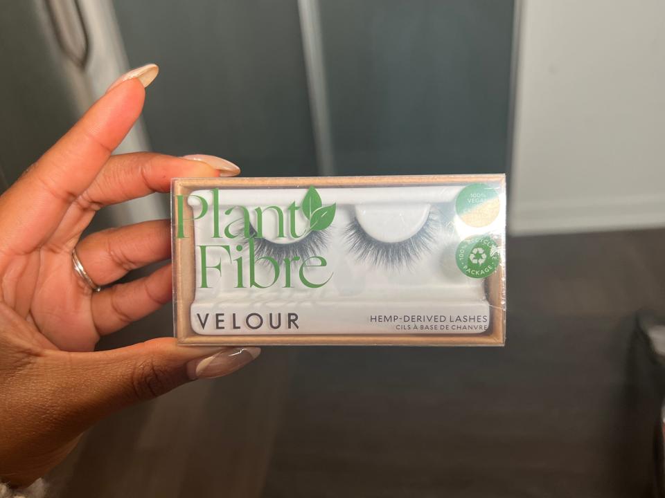 The writer holds a package with false lashes with green text saying "Plant Fibre"