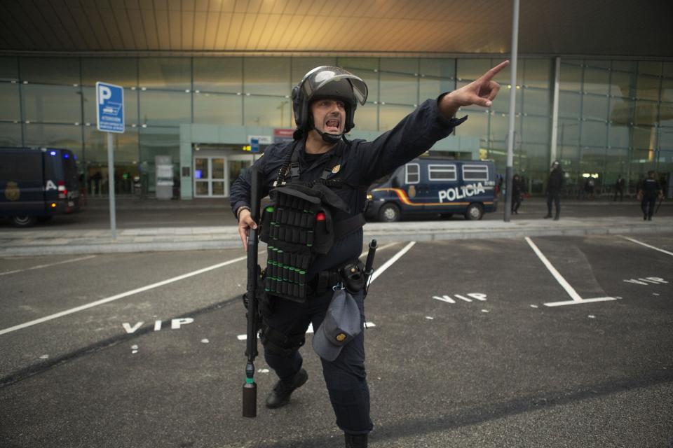 In this Monday, Oct. 14, 2019 photo, a Spanish police gives instructions to other police members, not pictured, during a demonstration at El Prat airport, outskirts of Barcelona, Spain. Riot police engaged in a running battle with angry protesters outside Barcelona's airport Monday after Spain's Supreme Court convicted 12 separatist leaders of illegally promoting the wealthy Catalonia region's independence and sentenced nine of them to prison. (AP Photo/Joan Mateu)