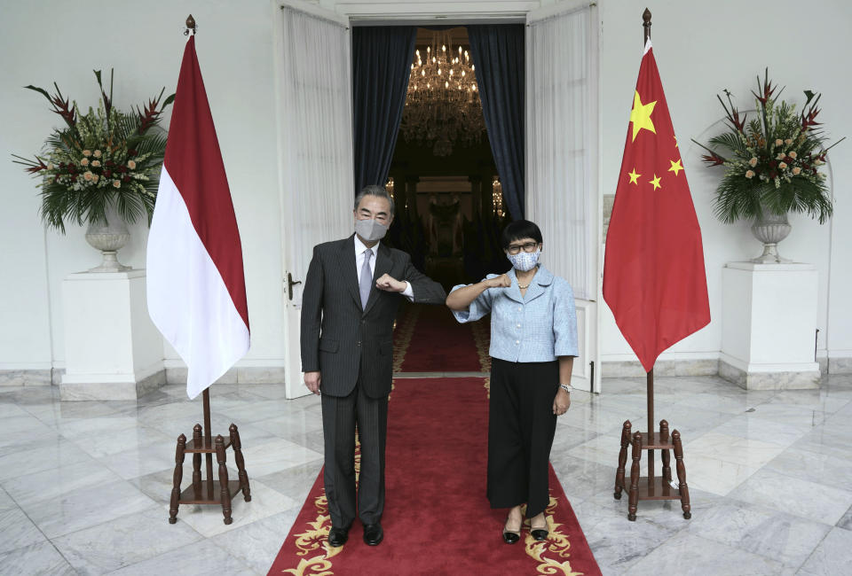 In this photo released by Indonesian Foreign Ministry, Chinese Foreign Minister Wang Yi, left, poses for photographers with his Indonesian counterpart Retno Marsudi during their meeting in Jakarta, Indonesia, Wednesday, Jan. 13, 2021. Wang pledged that China will help Indonesia defeat the coronavirus, including providing vaccines and the strengthen economic cooperation with Indonesia in addition to strengthening cooperation in the health sector in overcoming the COVID-19 pandemic. (Indonesian Foreign Ministry via AP)