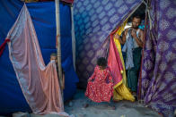 Kids play as Salimullah, 35, a Rohingya refugee comes out of his tent at a refugee camp alongside the banks of the Yamuna River in the southeastern borders of New Delhi, sprawling Indian capital, July 1, 2021. Millions of refugees living in crowded camps are waiting for their COVID-19 vaccines. For months, the World Health Organization urged countries to prioritize immunizing refugees, placing them in the second priority group for at-risk people, alongside those with serious health conditions. (AP Photo/Altaf Qadri)