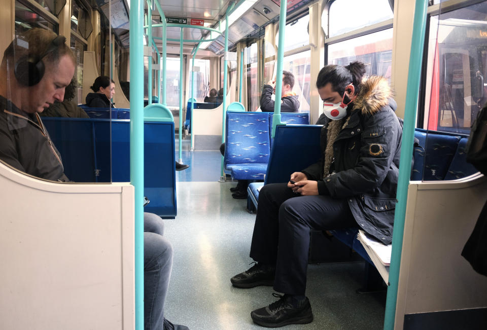 A passenger wearing a mask on a DLR train heading toward Canary Wharf, London, the day after Prime Minister Boris Johnson called on people to stay away from pubs, clubs and theatres, work from home if possible and avoid all non-essential contacts and travel in order to reduce the impact of the coronavirus pandemic.