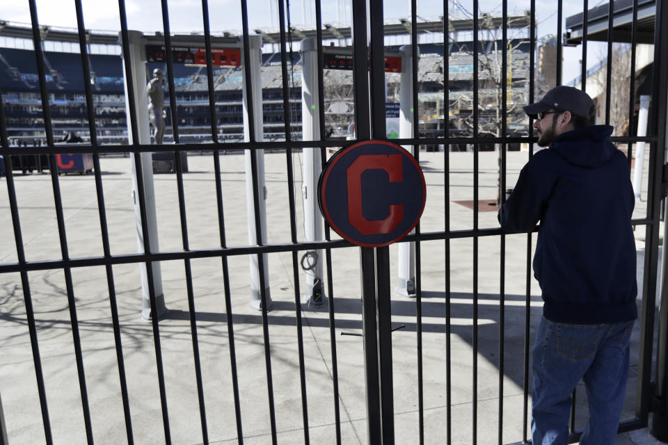 FILE - In this March 26, 2020, file photo, Jason Hackedorn looks into Progressive Field, home of the Cleveland Indians baseball team, in Cleveland. With the distinct possibility of pro sports resuming in empty venues, a recent poll suggests a majority of U.S. fans wouldn't feel safe attending games anyway without a coronavirus vaccine.(AP Photo/Tony Dejak, File)
