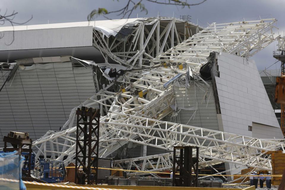 Workers stand next to a crane that collapsed on the site of the Arena Sao Paulo stadium, known as "Itaquerao", which will host the opening soccer match of the 2014 World Cup, in Sao Paulo