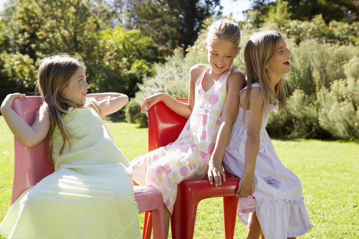 three girls playing musical chairs in garden