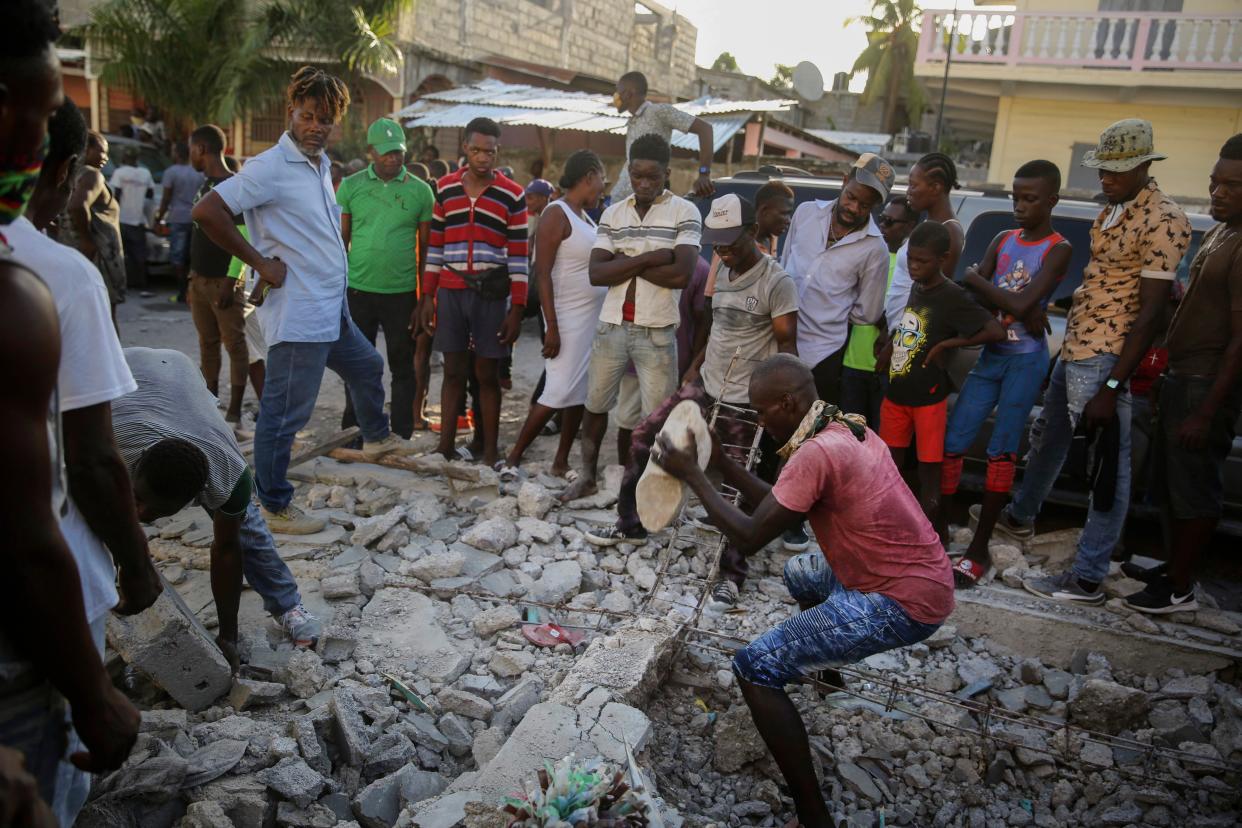 A man digs with a stone through the rubble of a house destroyed by the earthquake in Les Cayes, Haiti on Sunday, Aug. 15, 2021.