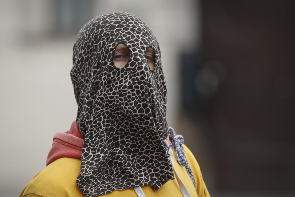 A man wears a mask as demonstrators gather to protest the COVID-19 preventative measures downtown Prague, Czech Republic, Wednesday, Oct. 28, 2020. Coronavirus infections in the Czech Republic have again jumped to record levels amid new restrictive measures imposed by the government to curb the spread. (AP Photo/Petr David Josek)