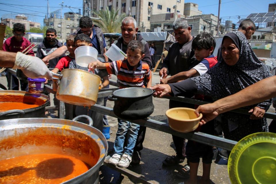 Palestinians gather to receive food cooked by a charity kitchen, amid shortages of aid supplies, after Israeli forces launched a ground and air operation in the eastern part of Rafah (REUTERS)