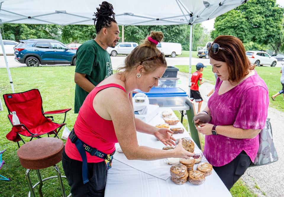 (Right) Jaime Pulliam from Milwaukee purchases baked goods from (center) Angela Green and (left) Kevin Green of Green Baked Goods at the Jackson Park Farmers Market on Thursday, July 21, 2022 in Milwaukee, Wis.