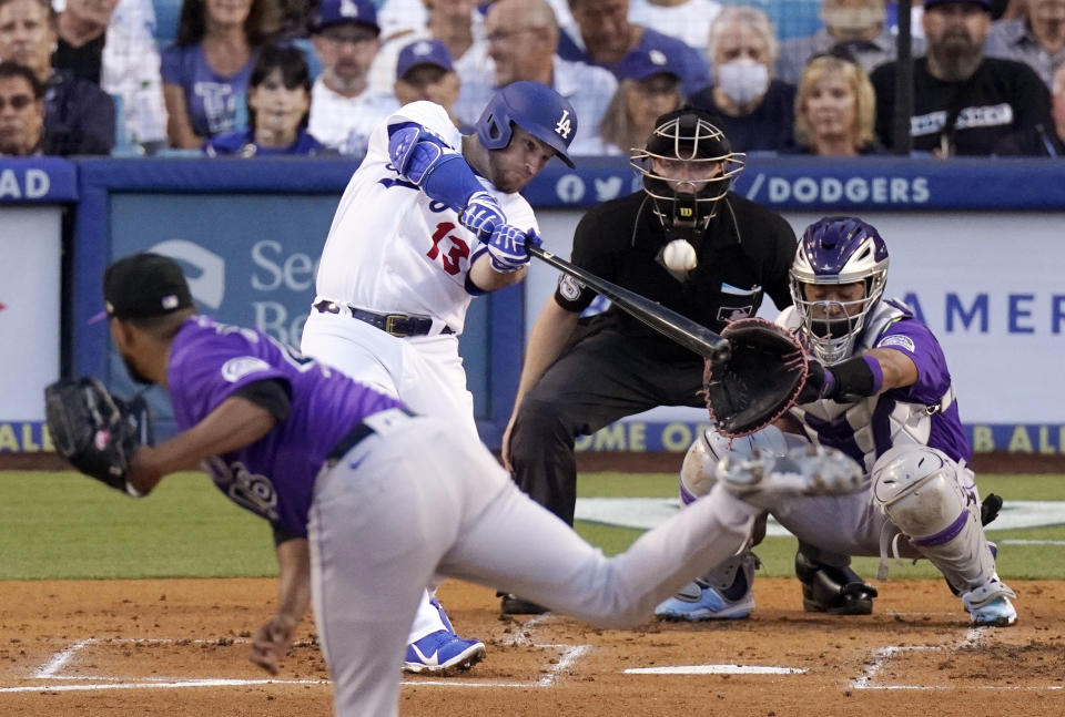 Los Angeles Dodgers' Max Muncy, second from left, hits a two-run home run as Colorado Rockies starting pitcher German Marquez, left, watches along with catcher Elias Diaz, right, and home plate umpire Junior Valentine during the second inning of a baseball game Tuesday, July 5, 2022, in Los Angeles. (AP Photo/Mark J. Terrill)