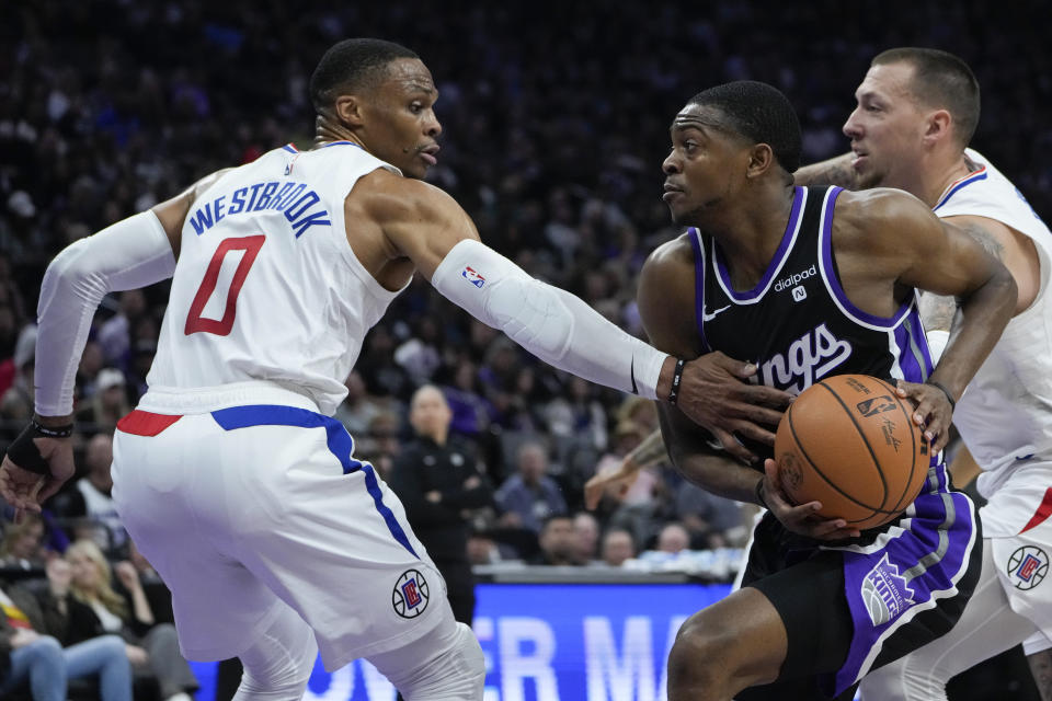 Sacramento Kings guard De'Aaron Fox, right, moves the ball while defended by Los Angeles Clippers guard Russell Westbrook (0) during the first half of an NBA basketball game Tuesday, April 2, 2024, in Sacramento, Calif. (AP Photo/Godofredo A. Vásquez)