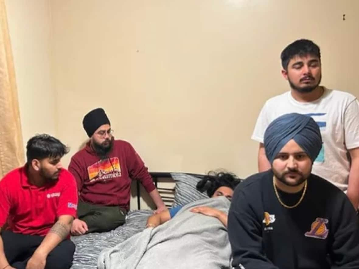 Gagandeep Singh, who is lying down, is surrounded by friends. He was allegedly punched and kicked at a bus stop and had his turban removed. (GoFundMe - image credit)