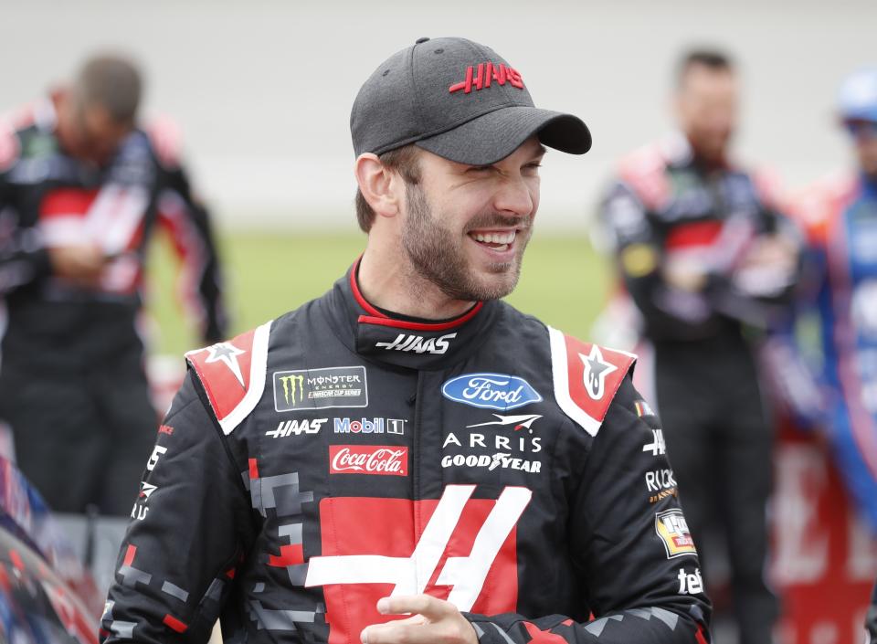 FILE - Daniel Suarez stands next to his car before a NASCAR cup series auto race at Michigan International Speedway in Brooklyn, Mich. in this Monday, June 10, 2019, file photo. New NASCAR team Trackhouse Racing has brought entertainer Pitbull on as an ownership partner for an organization making its debut next month at the Daytona 500. Trackhouse was launched late last year by former driver Justin Marks. The team has hired driver Daniel Suarez. It will not be NASCAR’s first pairing of a Hispanic driver and team owner. (AP Photo/Carlos Osorio, File)