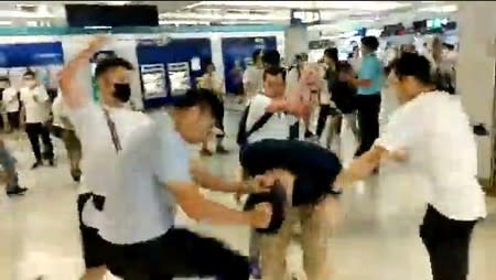 Social media video grab of men in white t-shirts and face masks attacking anti-extradition bill demonstrators and reporters at a train station in Hong Kong