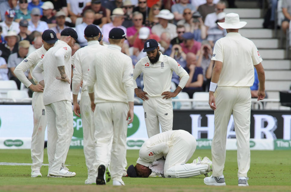 Teammates gather around England's Jonny Bairstow who reacts in pain after injuring his finger while collecting the ball during the third day of the third cricket test match between England and India at Trent Bridge in Nottingham, England, Monday, Aug. 20, 2018. (AP Photo/Rui Vieira)