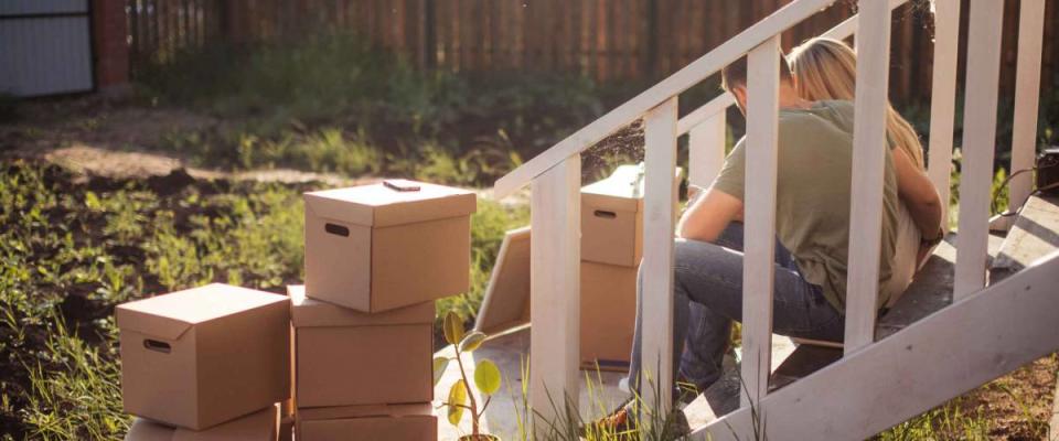 Family Outside House On Moving Day. cardboard boxes foreground near steps