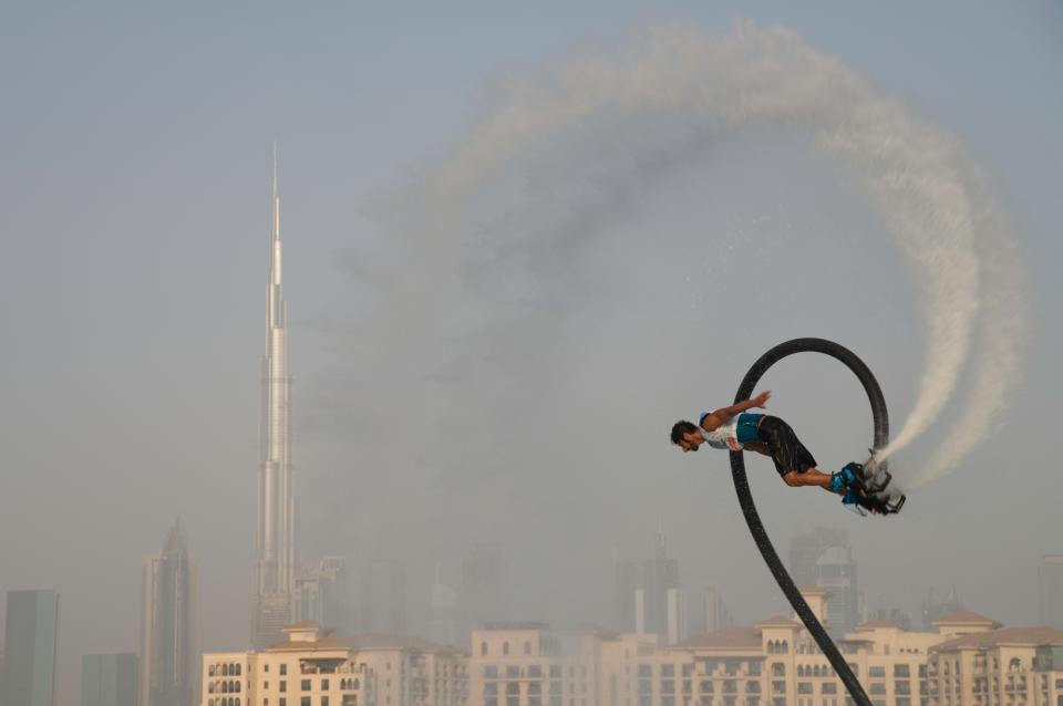 A man rides a flyboard with the Burj Khalifa, the world's tallest building, in the distance in Dubai, United Arab Emirates, Thursday, June 25, 2020. Dubai has begun to allow sporting events again amid the coronavirus pandemic and the Dubai International Marine Club hosted a water sports event Thursday to celebrate. (AP Photo/Jon Gambrell)